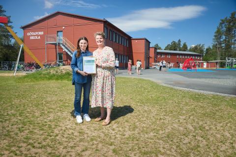 Two people standing on grass in front of a building