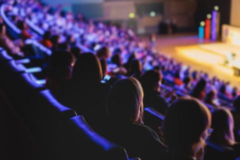 Audience in a modern conference hall listens to panel discussion
