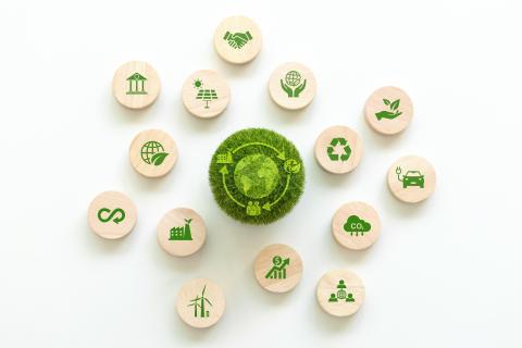 Green ball in the middle of a series of wooden buttons with logos relating to various parts of the circular economy, for example: renewable energy, working together, recycling, industry etc.