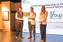 Three people standing on a stage in front of a screen about the award for Corporate Leadership in Circular Economy