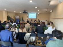 People sitting in a room for a presentation, with a screen with the words BATMASS Investment Forum.