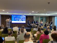 Photo of participants and speakers in a meeting room, with a screen with the writing 'Modelling to Policy: Circular Economy Pathways Towards Net-Zero'