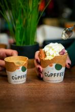 Two cupffee cups, one holding coffee, the other ice cream, both with bites taken out of them