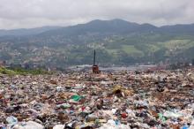 Piles of rubbish in front of green hills with houses on
