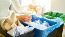 A person sorting household waste into separate bins for recycling.