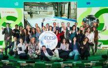 Group of people gathered arund a cardboard model of the ECESP logo