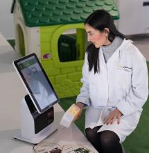 Woman in lab coat scanning a plastic ice cream box with a demonstrator