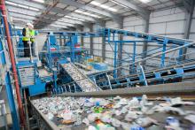 Wide shot of Businessman and worker talking on platform above conveyor belts in recycling plant