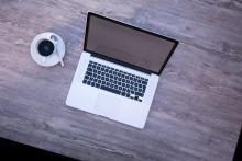 A laptop next to a coffee cup on a table